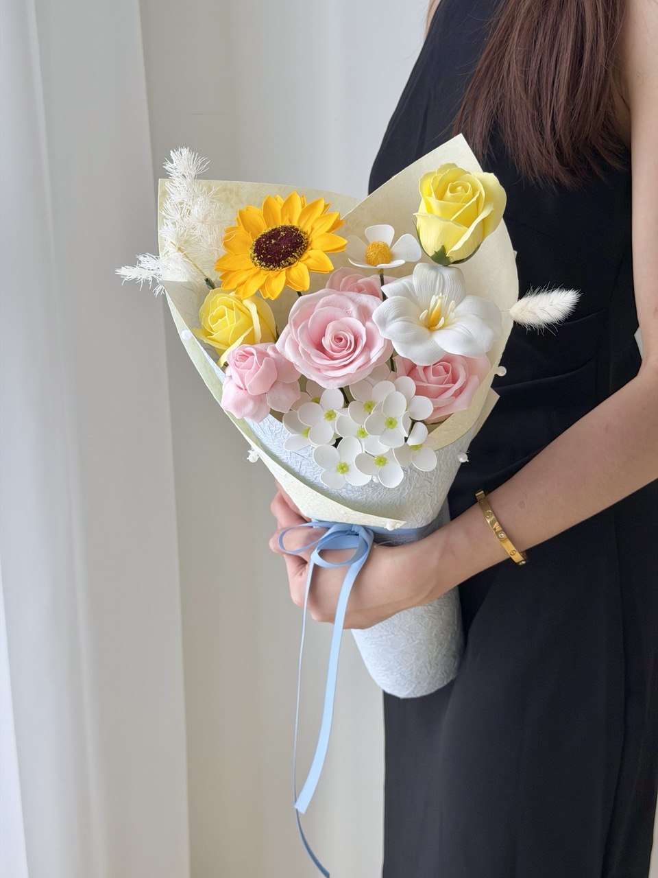 A girl wearing a black dress is holding a small bouquet of soap flower, perfect for graduation at University at Subang Jaya.