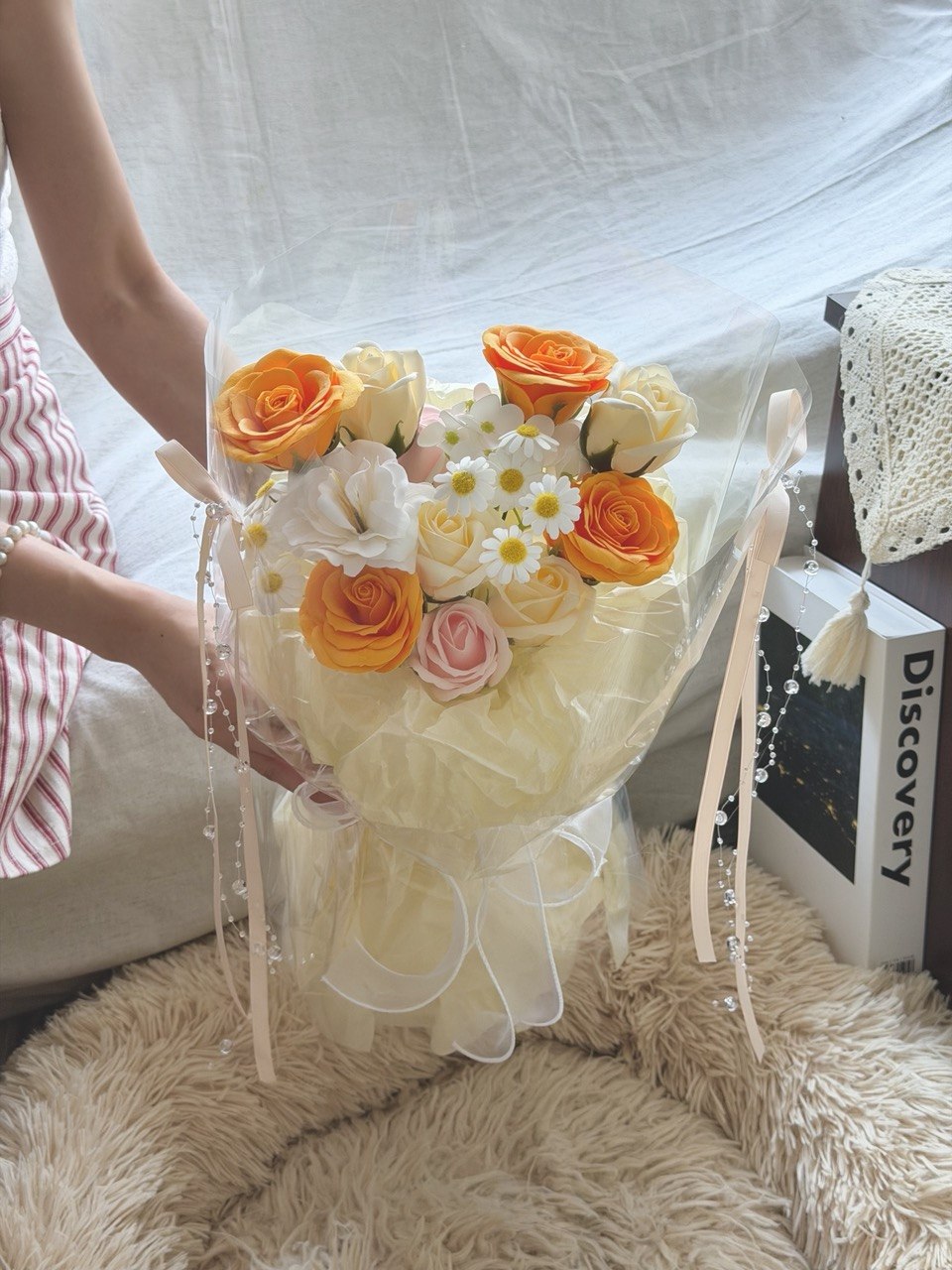 Beautiful soap flower bouquet with orange roses and white blooms in round wrap, suitable for birthday and anniversary gifts.