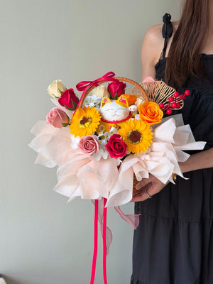 Person holding a soap flower basket with colorful flowers and a cat figurine against a plain background perfect for business opening gift.