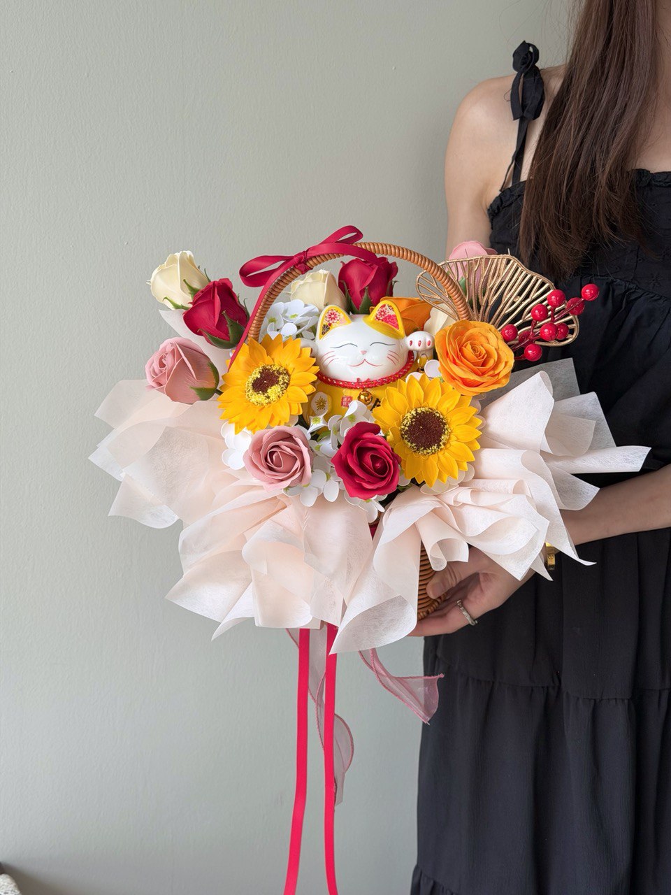 Person holding a soap flower basket with colorful flowers and a cat figurine against a plain background perfect for business opening gift.