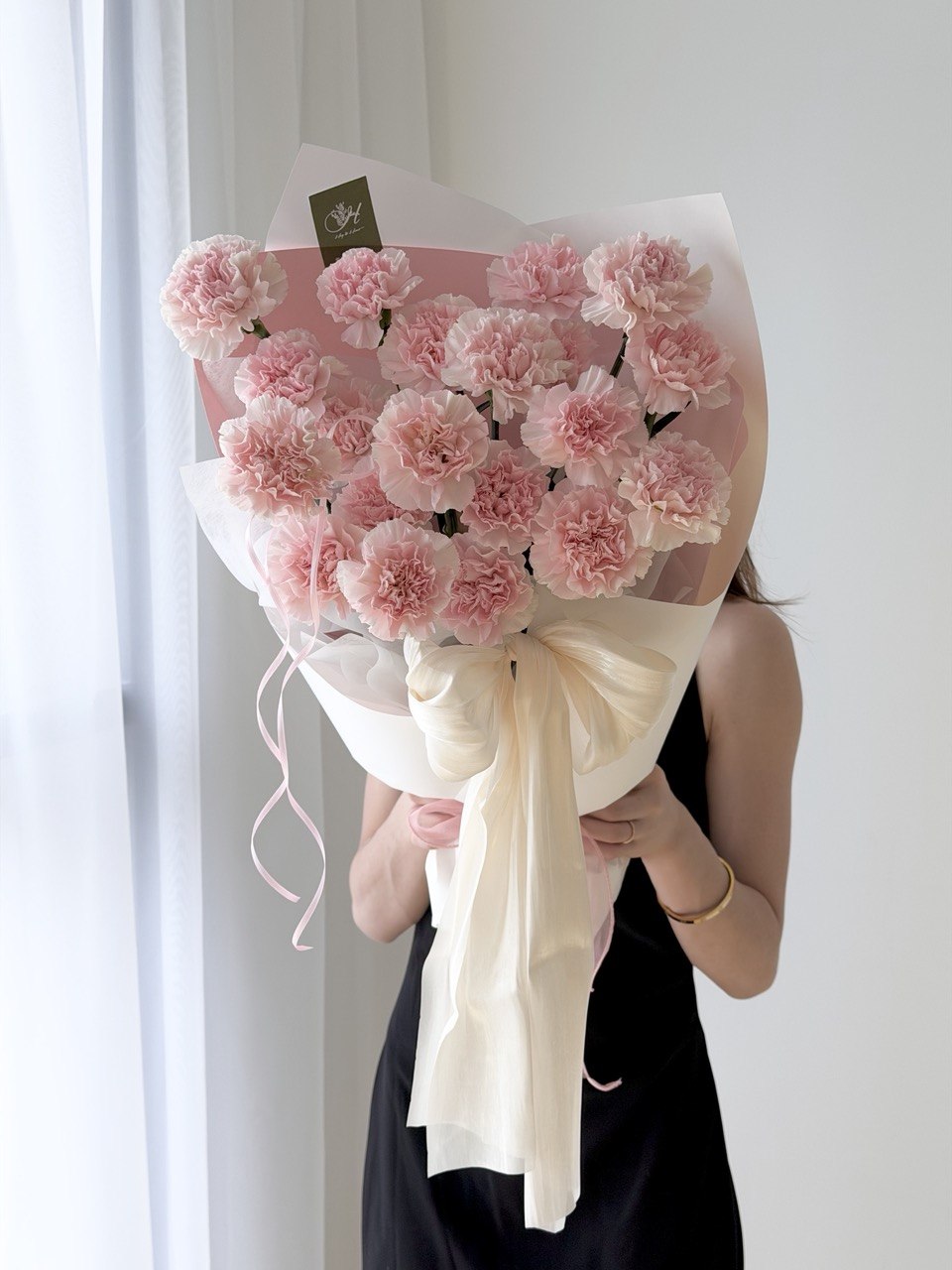 A girl is holding a bouquet of carnation for mother's day gift at Subang Jaya prepared by hug and heart florist subang jaya.