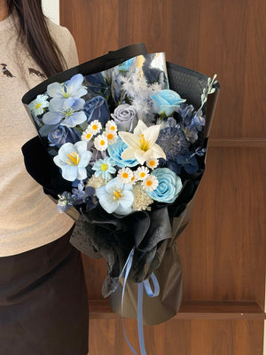 Luxury everlasting soap flower bouquet featuring blue roses, white lily, tulips, and elegant black wrapping, ideal for graduation, opening ceremony, and corporate gifting.