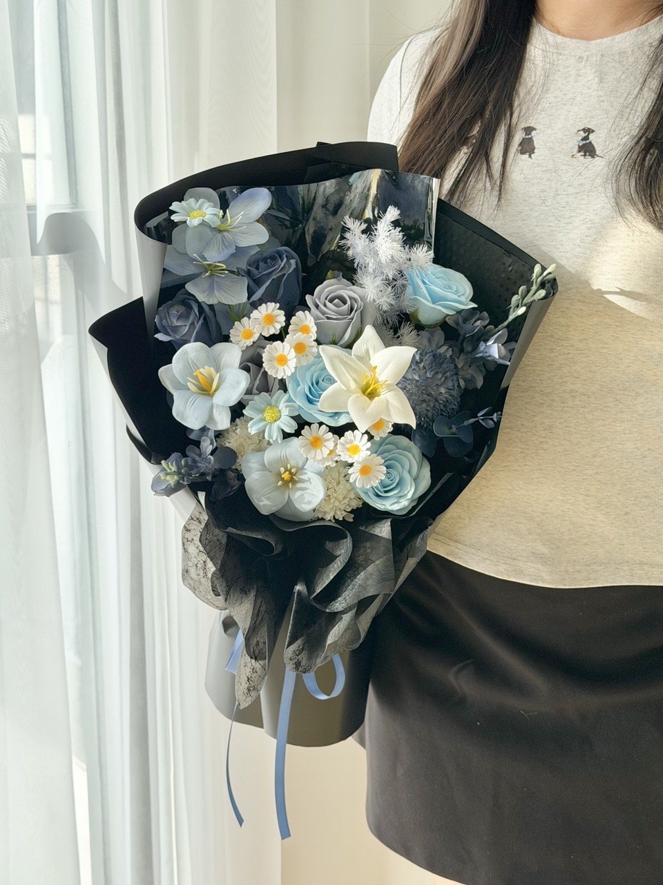 Artificial soap flower bouquet in dark blue and black theme with realistic blue roses, elegant white lily, tulips, and white daisies for lasting floral gifts.