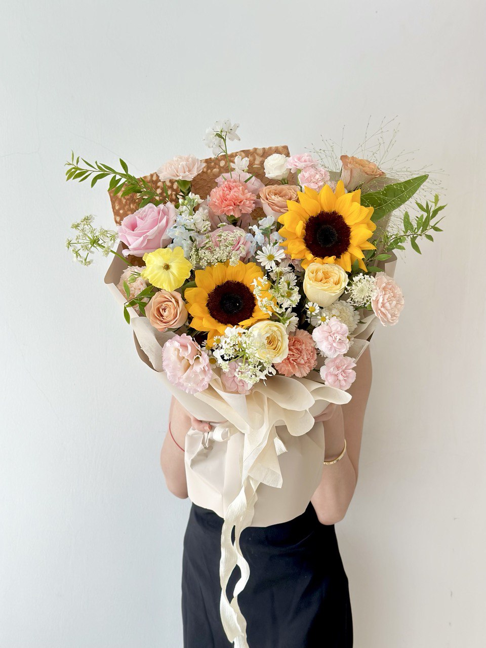 Graduation sunflower bouquet with soft pastel blooms, held stylishly for a modern and memorable university celebration.