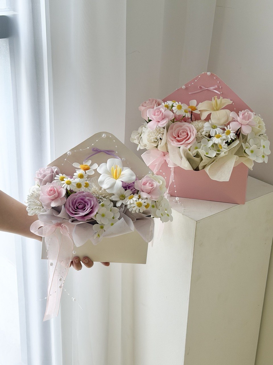 Premium envelope soap flower arrangement featuring blush pink roses, lavender rose, white flowers, and elegant ribbon for romantic occasions.