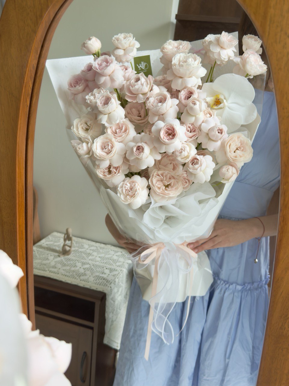 A girl is holding a bouquet of kiss of fairy rose spray in front of a mirror at her own studio at Kuala Lumpur.