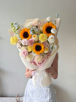 A graduate is holding a sunflower bouquet from hug and heart florist at sunway geo avenue subang jaya.