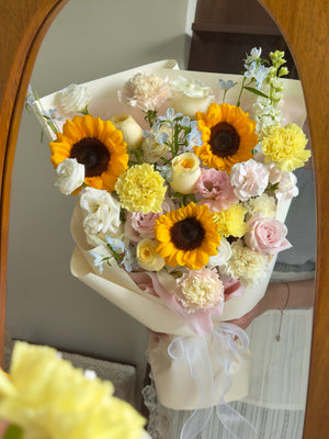 A girl is holding a sunflower graduation bouquet in front of a mirror.