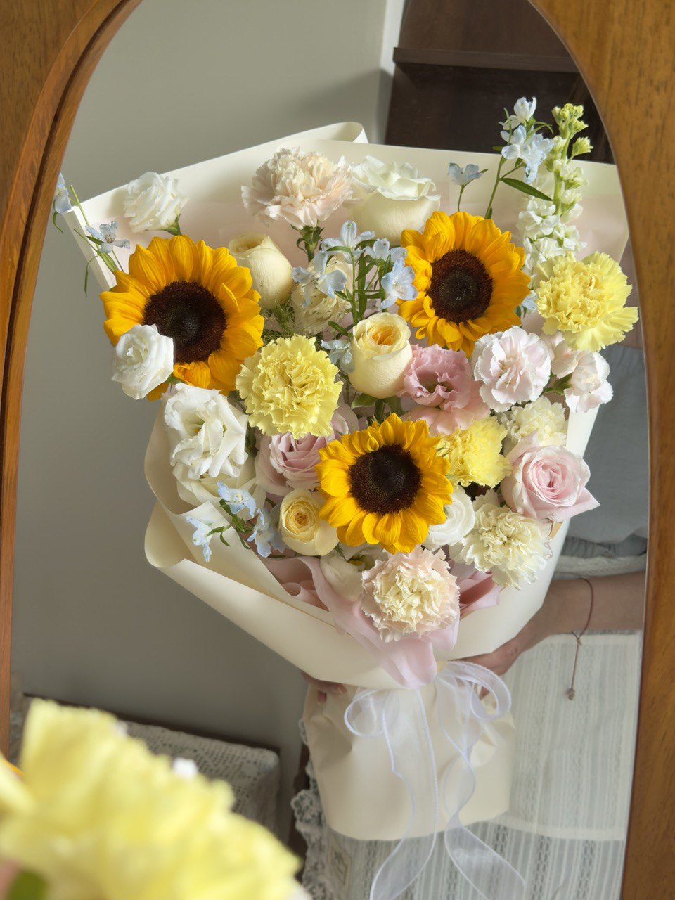 A girl is holding a sunflower graduation bouquet in front of a mirror.