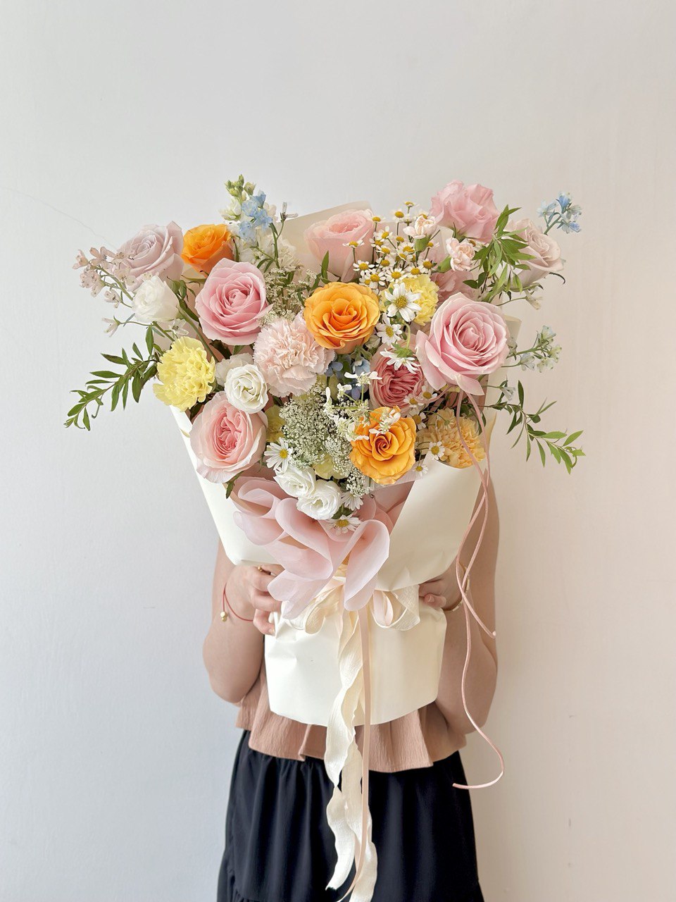 Bouquet of flowers held by a person against a plain background