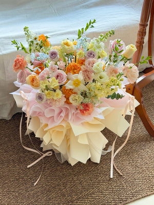 A bouquet of mixed rose with pink rose, lilac rose, champagne rose, white tulip and green fillers wrapped on ballet style.