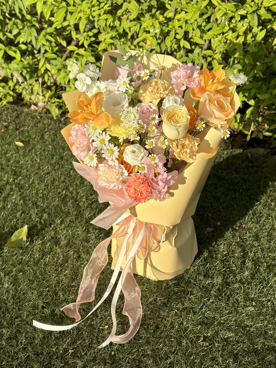 Woman holding a cheerful bouquet filled with warm-toned roses, carnations, and playful daisies.