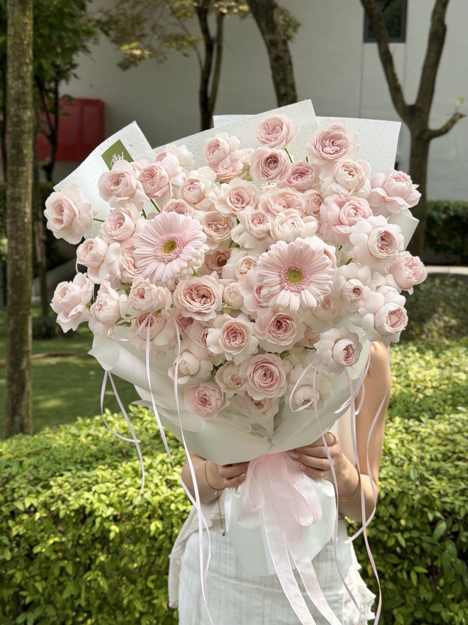 A bouquet of Kiss of Fairy rose spray with light pink gerbera is held by a girl at outdoor perfect for birthday celebration at Kuala Lumpur.