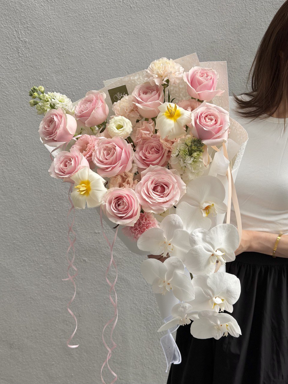 Modern hand bouquet combining pink roses, white phalaenopsis orchids, and fresh tulips, ideal for luxury gifts and memorable floral moments.